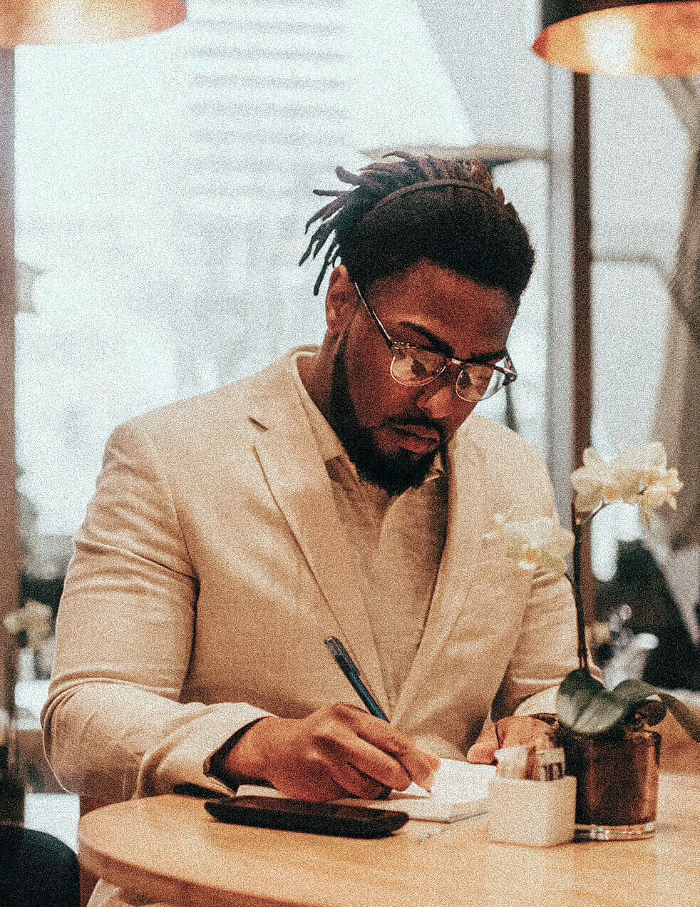Corey writing in a notebook at a cafe table